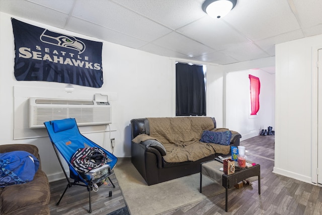 living room with an AC wall unit, wood-type flooring, and a paneled ceiling