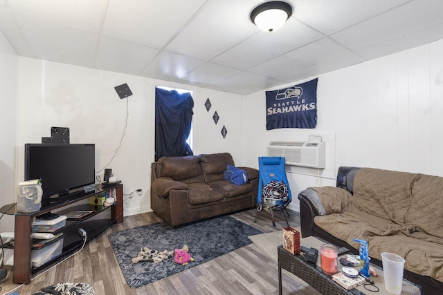 living room with hardwood / wood-style floors, a paneled ceiling, and a wall mounted AC