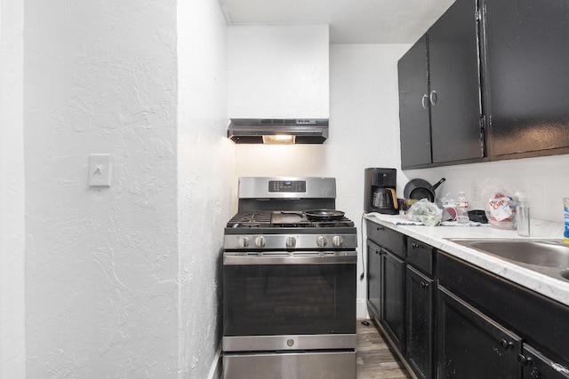 kitchen with sink, stainless steel gas stove, extractor fan, and dark hardwood / wood-style floors