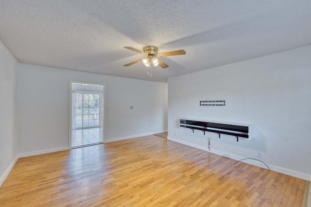 empty room featuring ceiling fan, light wood-type flooring, and a textured ceiling