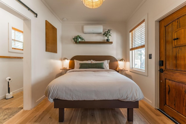 bedroom featuring light hardwood / wood-style flooring, crown molding, and a wall mounted air conditioner