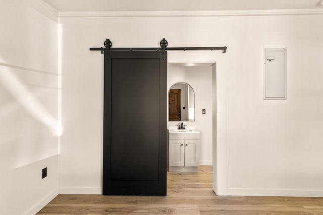 interior space with sink, light hardwood / wood-style flooring, ornamental molding, and a barn door