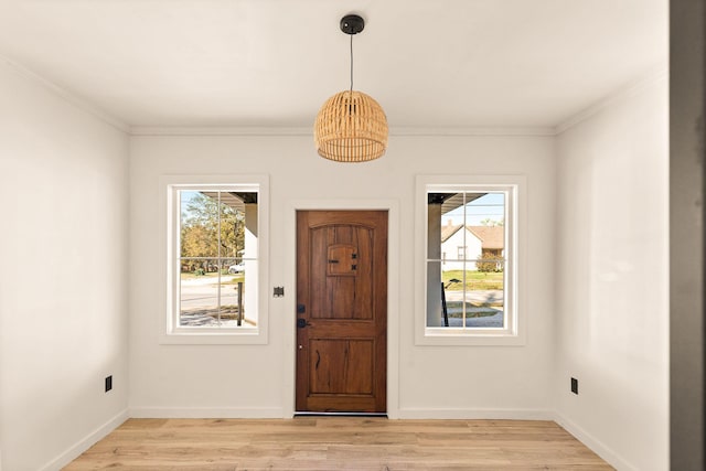 entrance foyer with plenty of natural light, ornamental molding, and light hardwood / wood-style flooring