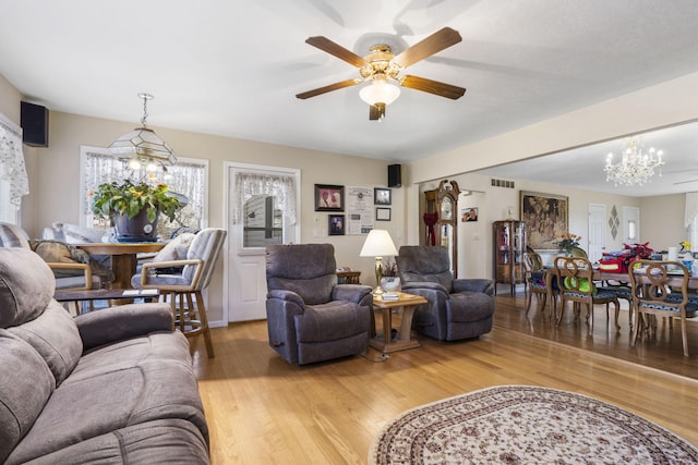 living room featuring ceiling fan with notable chandelier and hardwood / wood-style floors