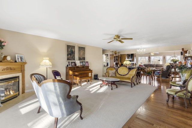 living room featuring ceiling fan with notable chandelier, hardwood / wood-style floors, and a premium fireplace