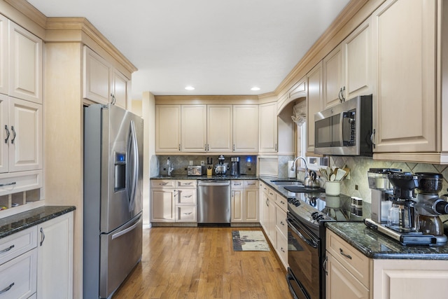 kitchen with stainless steel appliances, decorative backsplash, light hardwood / wood-style flooring, and dark stone counters