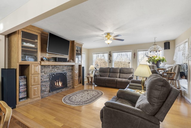 living room featuring ceiling fan, light wood-type flooring, and a fireplace