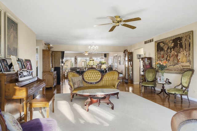 living room with ceiling fan with notable chandelier and dark hardwood / wood-style floors