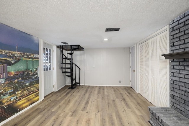 basement featuring light hardwood / wood-style floors and a textured ceiling