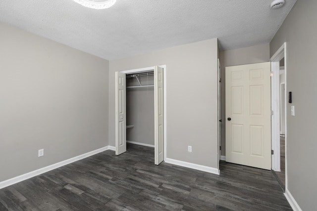 unfurnished bedroom with a textured ceiling, a closet, and dark hardwood / wood-style floors