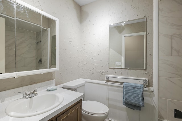 bathroom with toilet, vanity, and tiled shower