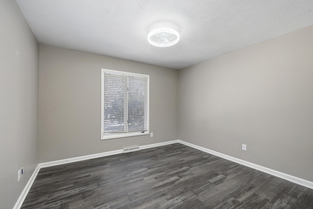 empty room featuring dark wood-type flooring and a textured ceiling