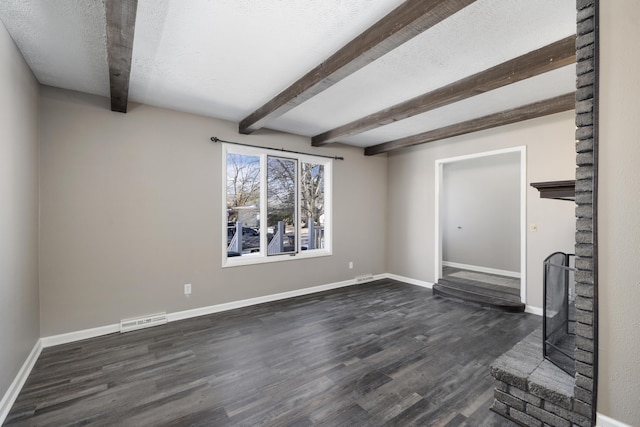 unfurnished living room featuring a textured ceiling, beam ceiling, and dark hardwood / wood-style floors