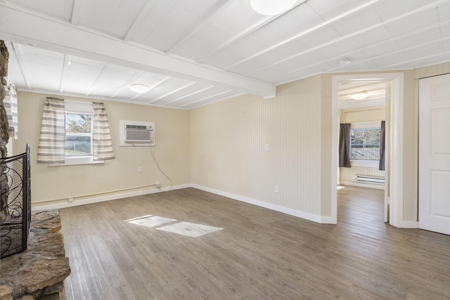 unfurnished living room with hardwood / wood-style flooring, beam ceiling, a stone fireplace, and a wall mounted air conditioner