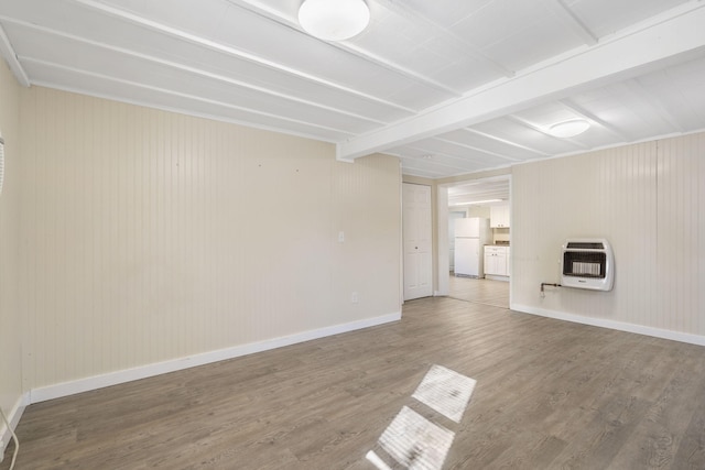 spare room featuring heating unit, hardwood / wood-style floors, and beamed ceiling