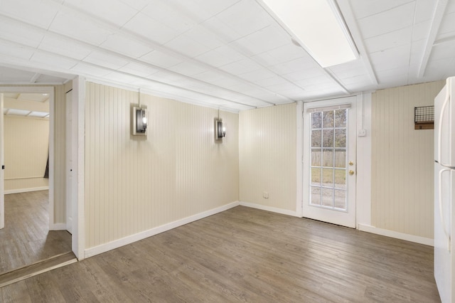 basement with white refrigerator and hardwood / wood-style flooring