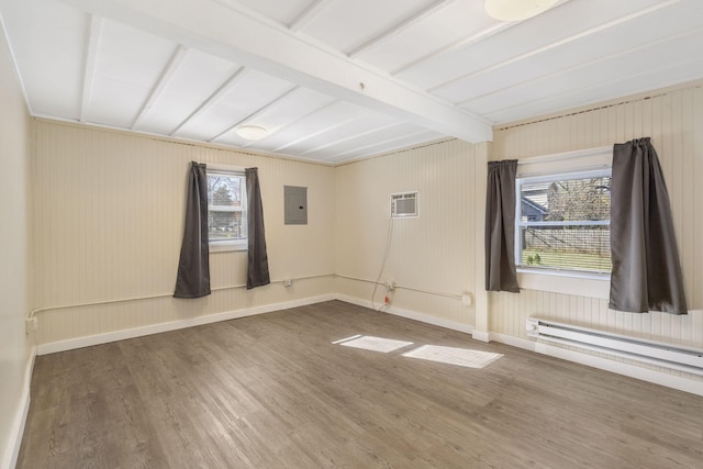 spare room with a baseboard heating unit, electric panel, a healthy amount of sunlight, and hardwood / wood-style floors