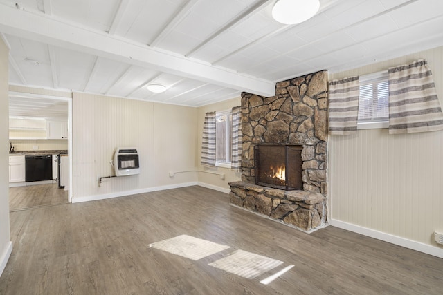 unfurnished living room with heating unit, a fireplace, hardwood / wood-style floors, and beamed ceiling