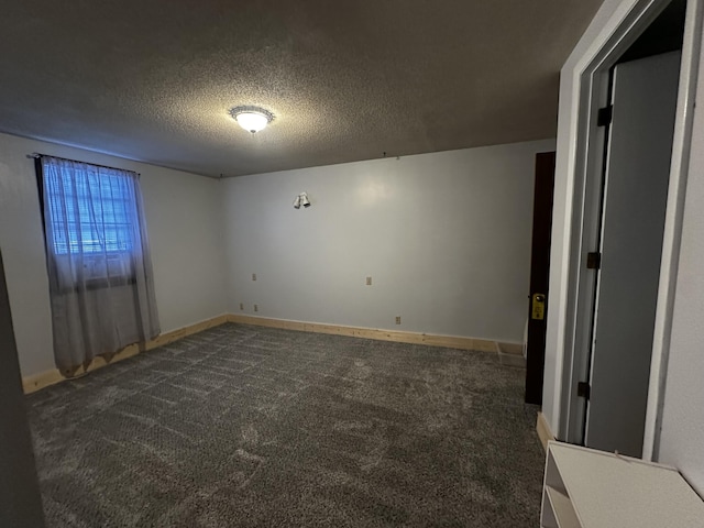 empty room with dark carpet and a textured ceiling