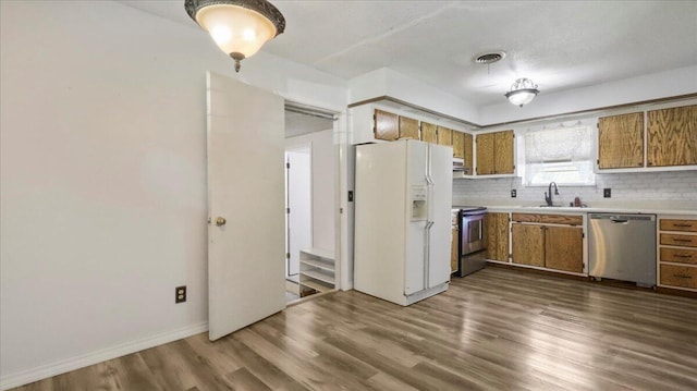 1933 Lynn Dr, West Plains, MO 65775 - kitchen with stainless steel appliances, brown cabinetry, light countertops, decorative backsplash, and dark wood-style flooring