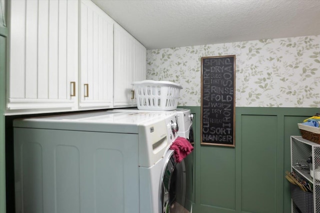 clothes washing area featuring cabinets, a textured ceiling, and washing machine and dryer