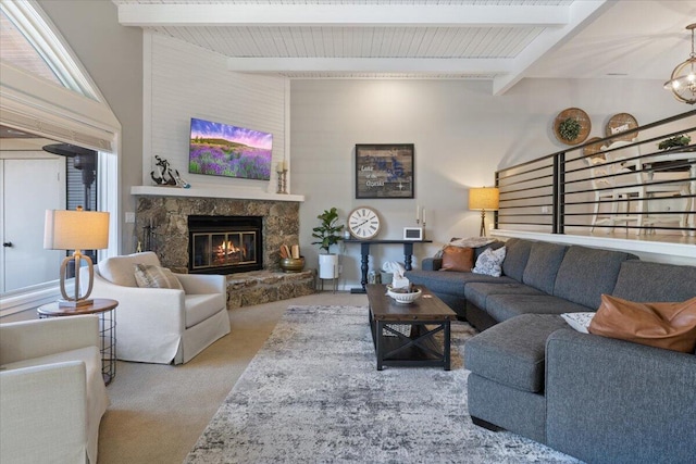 carpeted living room with beam ceiling and a stone fireplace