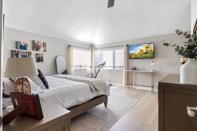 bedroom with ceiling fan, light hardwood / wood-style floors, and lofted ceiling