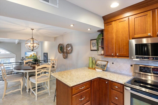 kitchen featuring light stone counters, appliances with stainless steel finishes, tasteful backsplash, and an inviting chandelier