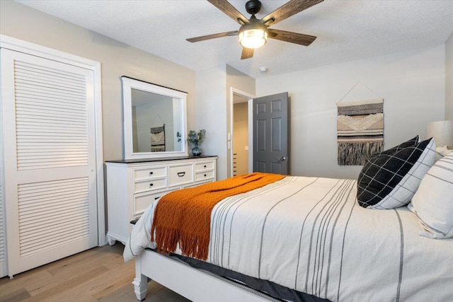 bedroom featuring ceiling fan, a closet, a textured ceiling, and light hardwood / wood-style floors