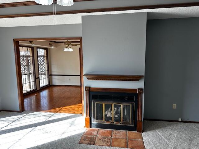 unfurnished living room with ceiling fan, a tile fireplace, and carpet floors