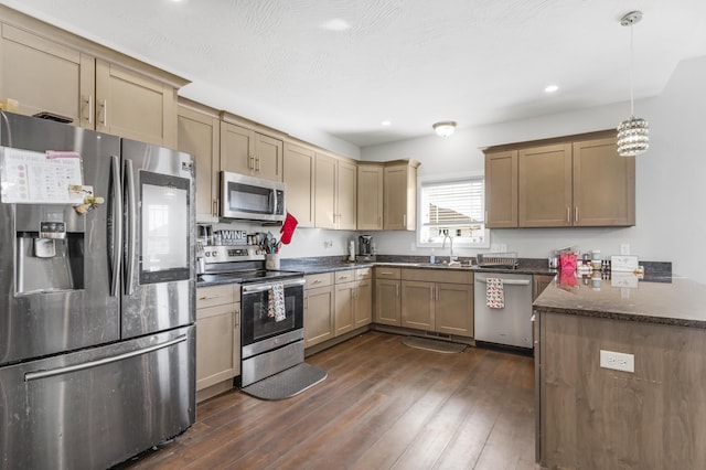 kitchen with kitchen peninsula, appliances with stainless steel finishes, dark wood-type flooring, hanging light fixtures, and sink