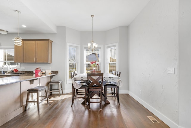 dining space with dark wood-type flooring, sink, and a notable chandelier