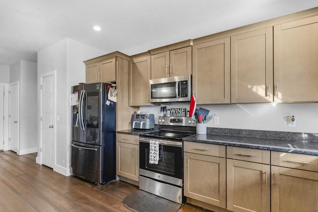 kitchen featuring dark hardwood / wood-style flooring, dark stone counters, and stainless steel appliances