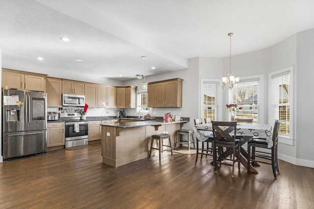 kitchen featuring a kitchen bar, kitchen peninsula, stainless steel appliances, a notable chandelier, and pendant lighting