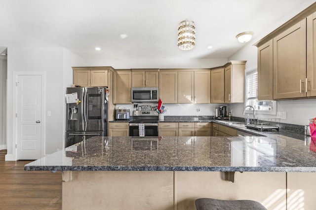 kitchen featuring decorative light fixtures, sink, stainless steel appliances, and a kitchen breakfast bar