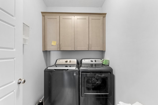 clothes washing area featuring separate washer and dryer and cabinets