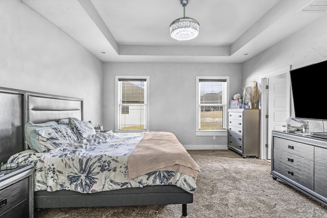 carpeted bedroom featuring a raised ceiling