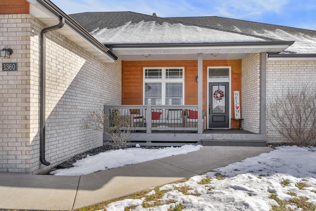 snow covered property entrance featuring covered porch