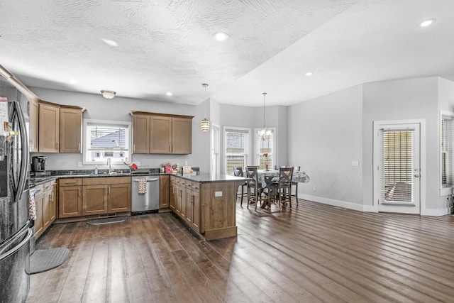 kitchen featuring a wealth of natural light, kitchen peninsula, stainless steel appliances, and hanging light fixtures