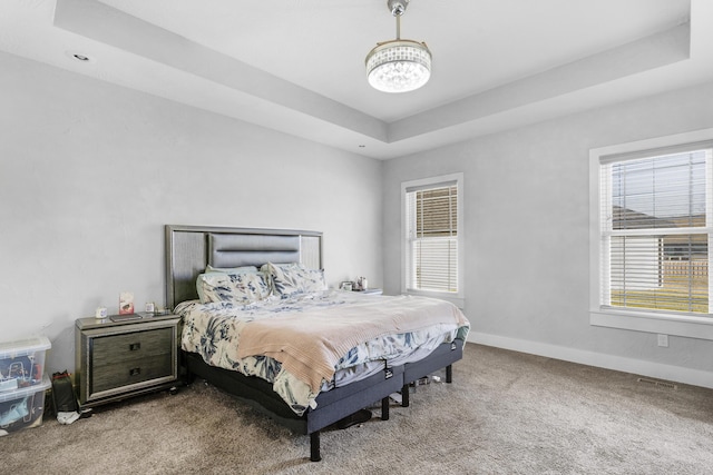 bedroom featuring carpet, a raised ceiling, and an inviting chandelier