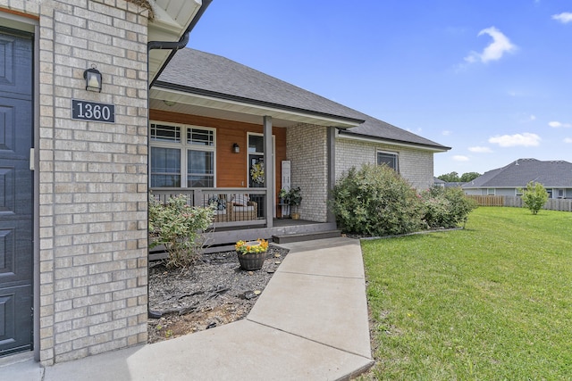1360 N Rainbow Ct, Nixa, MO 65714 - view of exterior entry featuring a porch, a lawn, brick siding, and roof with shingles