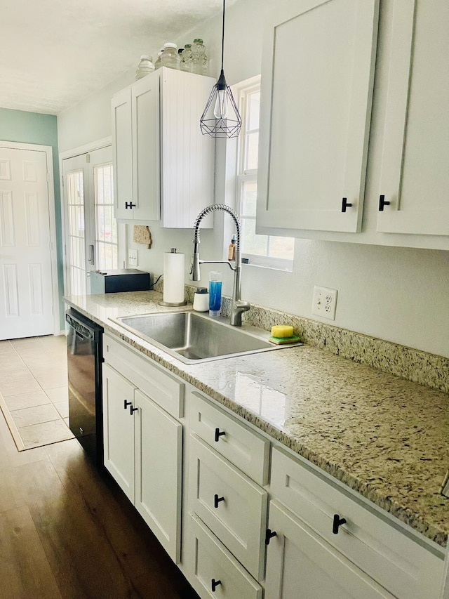 kitchen with white cabinetry, black dishwasher, decorative light fixtures, light stone counters, and sink