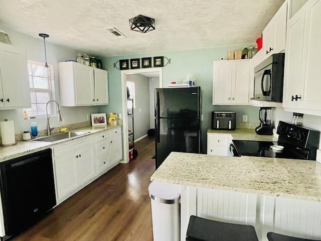 kitchen featuring black appliances, a kitchen bar, sink, hanging light fixtures, and white cabinets