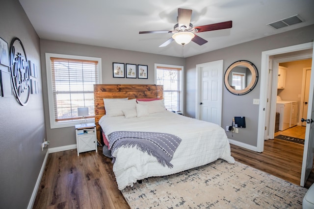 bedroom with dark wood-type flooring, ceiling fan, separate washer and dryer, and multiple windows