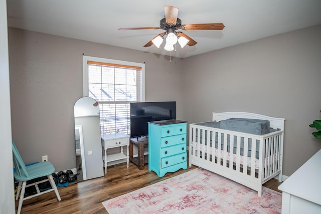 bedroom with ceiling fan, hardwood / wood-style floors, and a nursery area