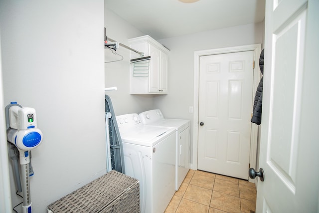 clothes washing area featuring cabinets, separate washer and dryer, and light tile patterned flooring