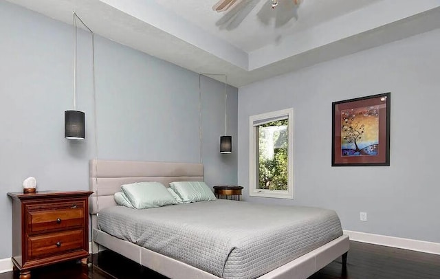 bedroom featuring ceiling fan, dark hardwood / wood-style floors, and a tray ceiling