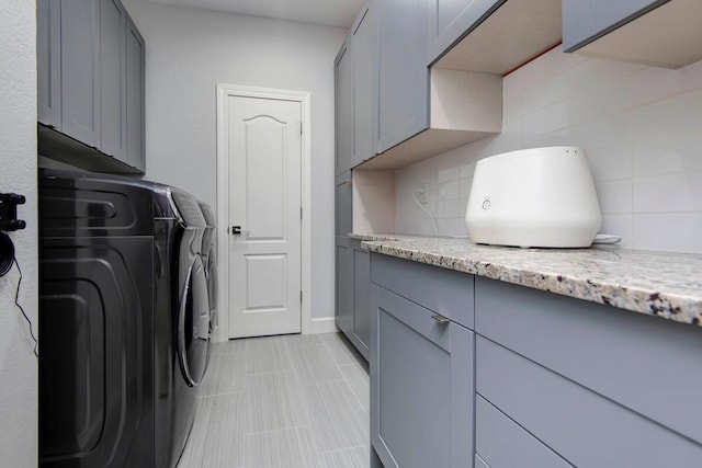 washroom featuring washing machine and clothes dryer and cabinets