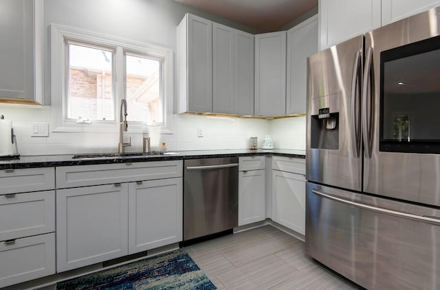 kitchen featuring white cabinets, sink, dark stone countertops, and stainless steel appliances