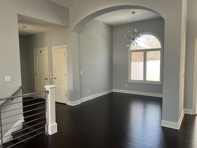 empty room featuring dark wood-type flooring and a chandelier